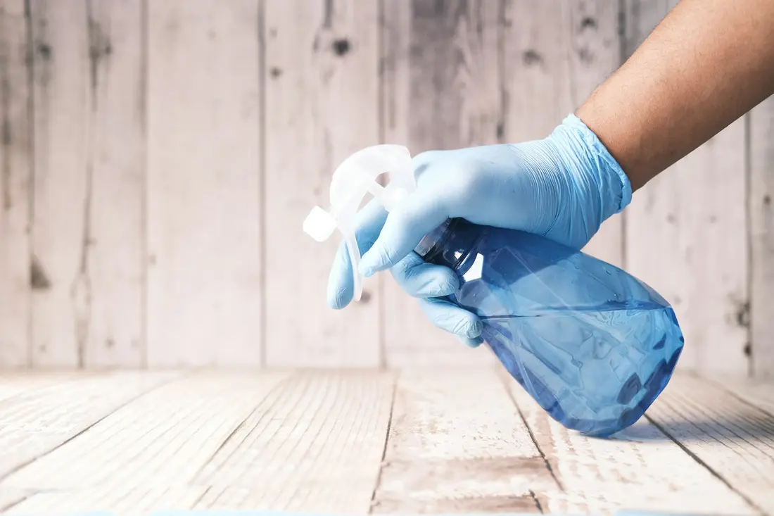 Reinigung mit Handschuhen und Sprühflasche